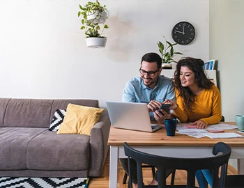a couple looks at their finances while sitting at a kitchen table