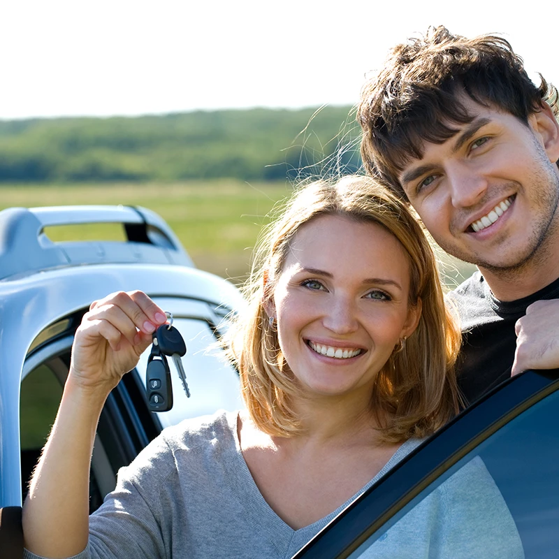 a young couple with keys to a new car