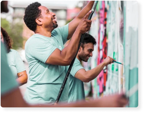 two men painting a mural on a wall