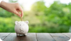 a hand putting money into a piggy bank