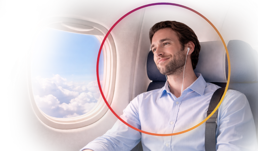 a man in an airplane looking out the window with headphones on